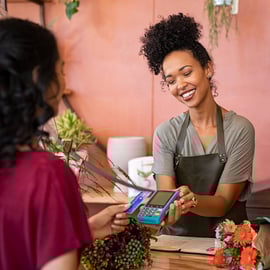 Small business owner utilizing technology to check out a customer